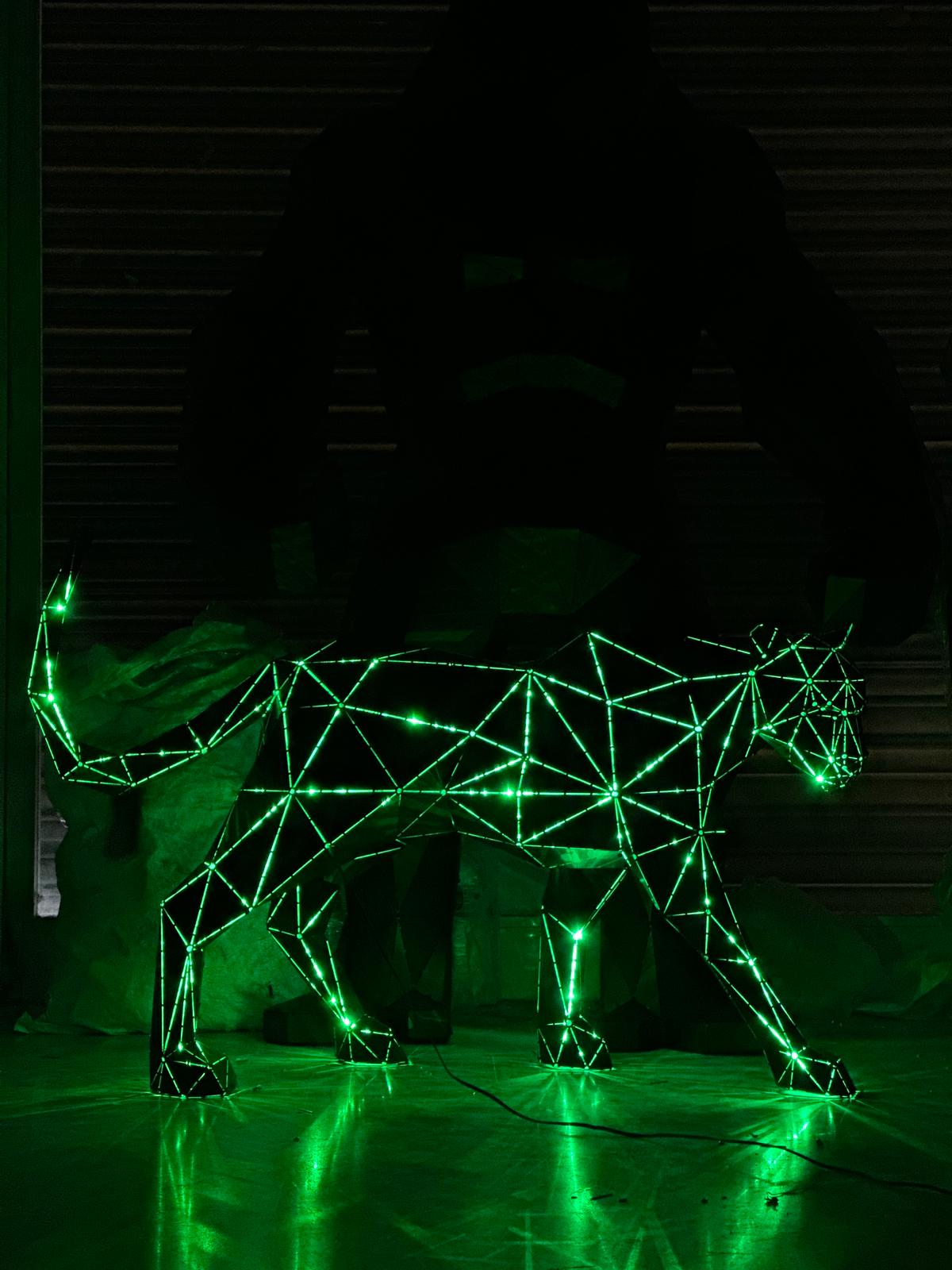 Green neon geometric wireframe sculpture of a prowling panther in a dark setting