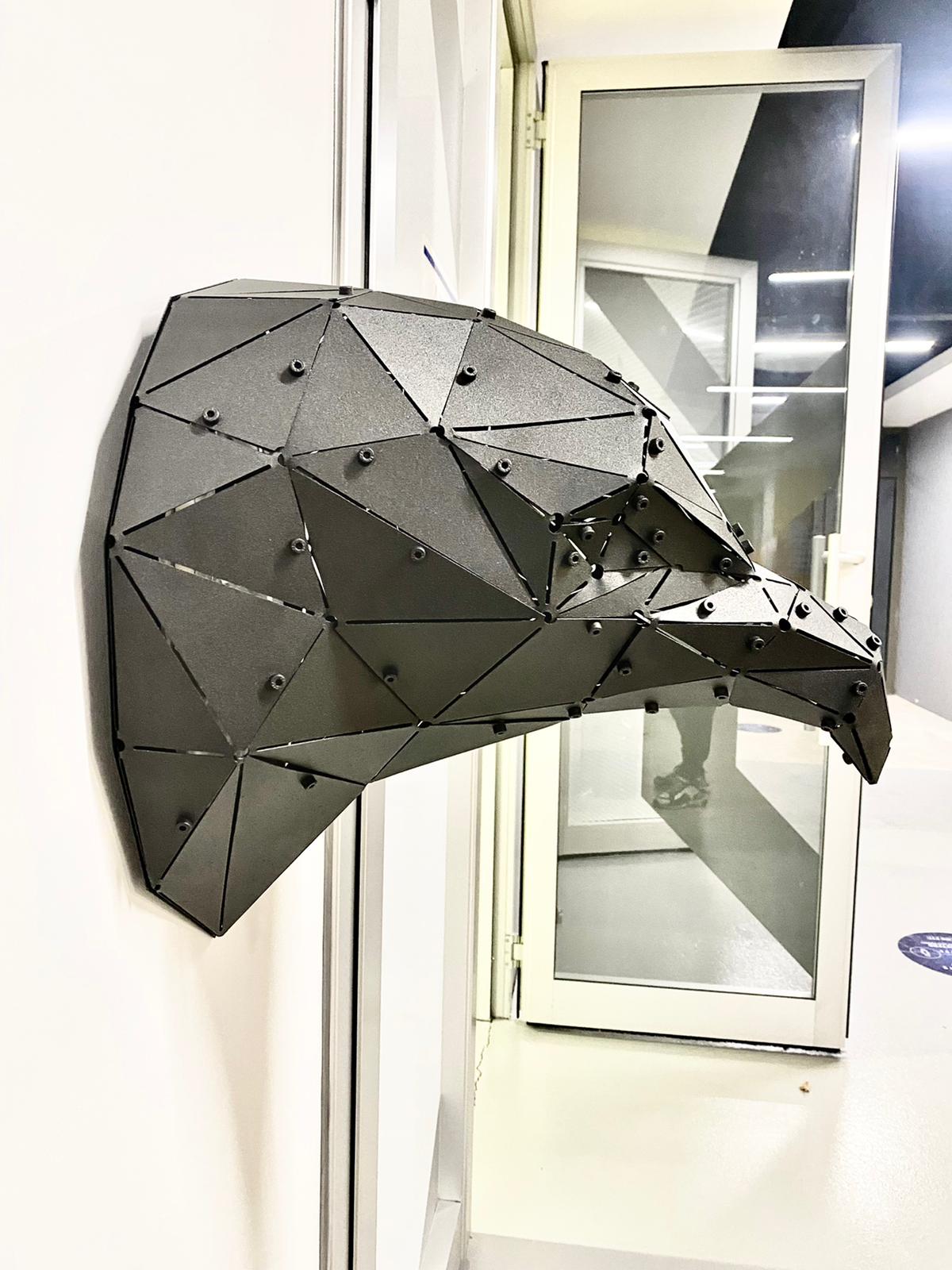 Low-poly handcrafted metal eagle head sculpture mounted on a white wall