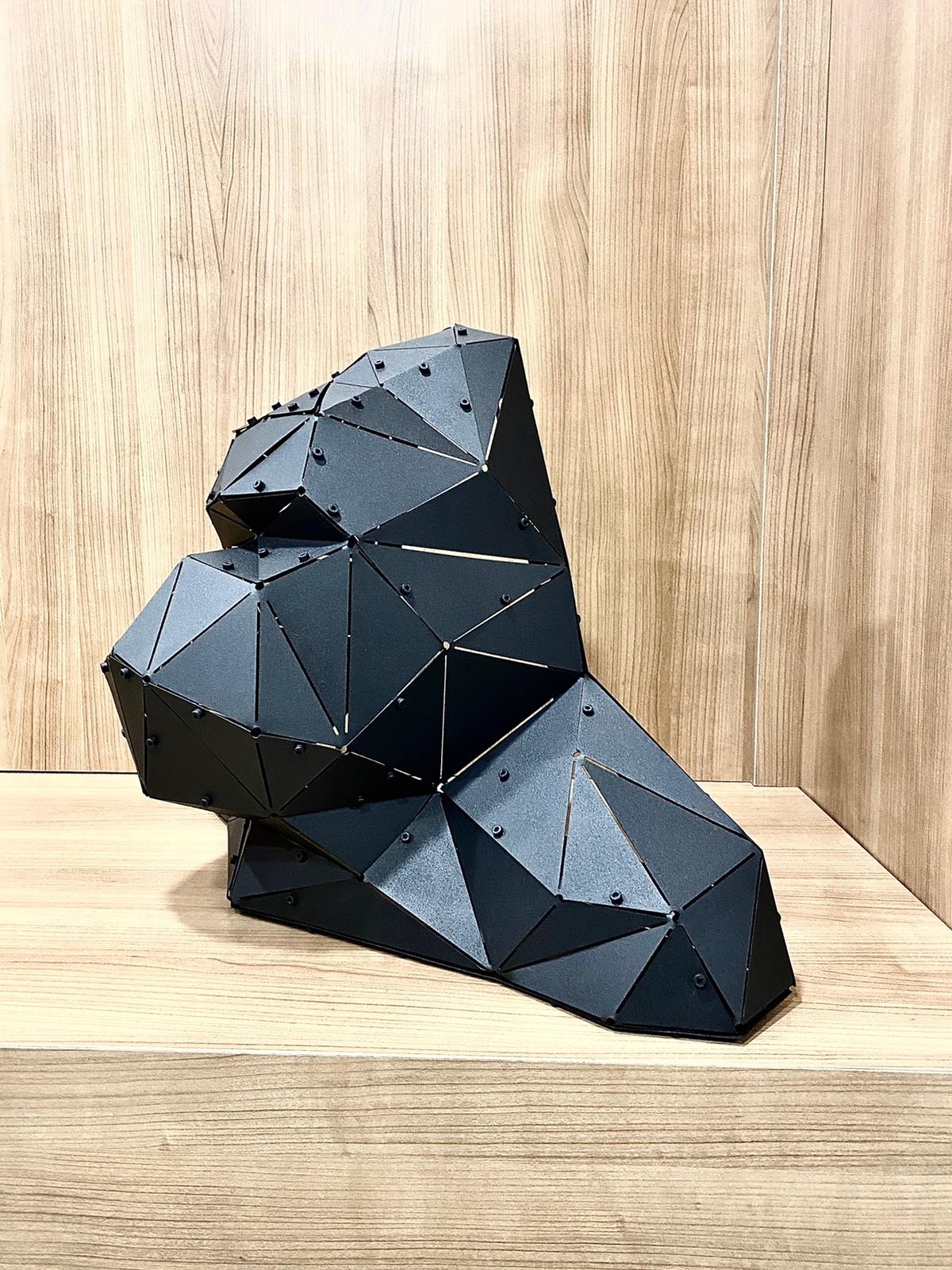 Modern low-poly black metal sculpture on a light wooden shelf