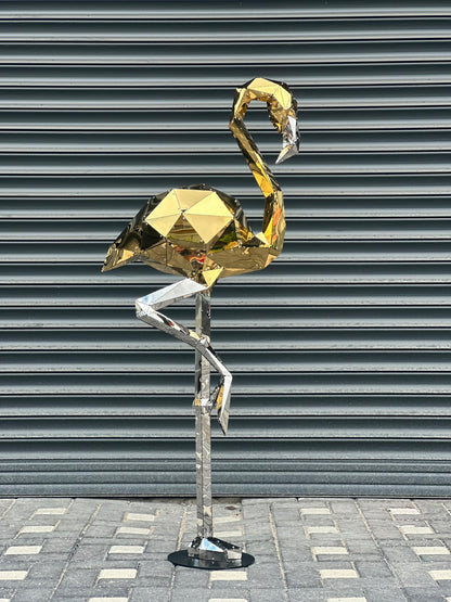 Low poly gold and silver metallic flamingo sculpture against a grey shutter background