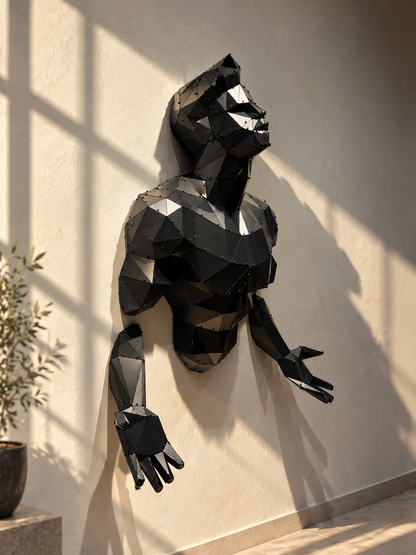 Emerging Man black geometric metal male torso wall sculpture emerging from a beige wall in sunlight