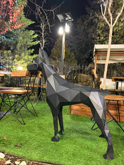 Geometric black metal dog sculpture on a green lawn at an outdoor restaurant setting