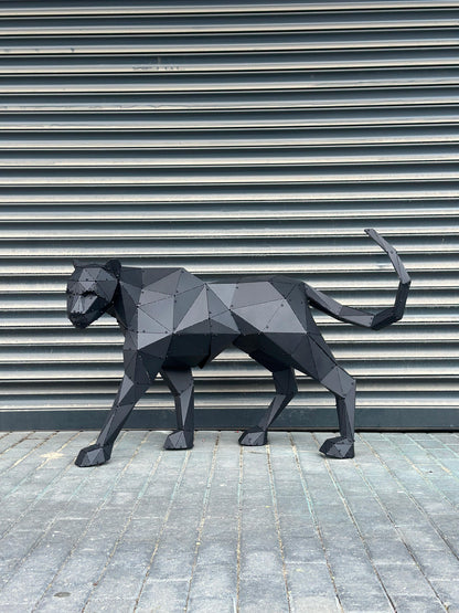 Geometric black metal panther sculpture standing against a grey shutter background.