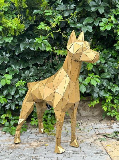 Geometric gold metal dog sculpture standing outdoors against a lush green leaf background