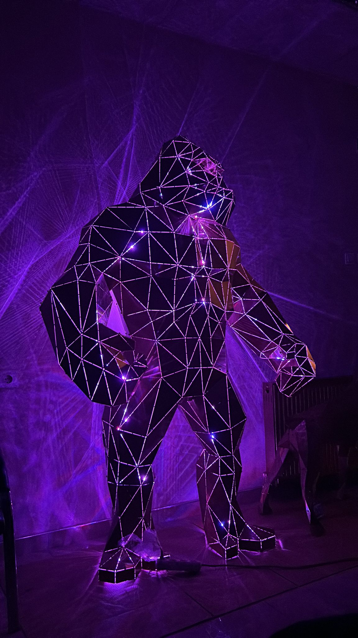 Geometric metal gorilla sculpture illuminated with purple light and sparkling details