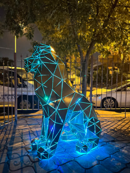 Geometric metal sitting lion sculpture illuminated with blue LED lights at night