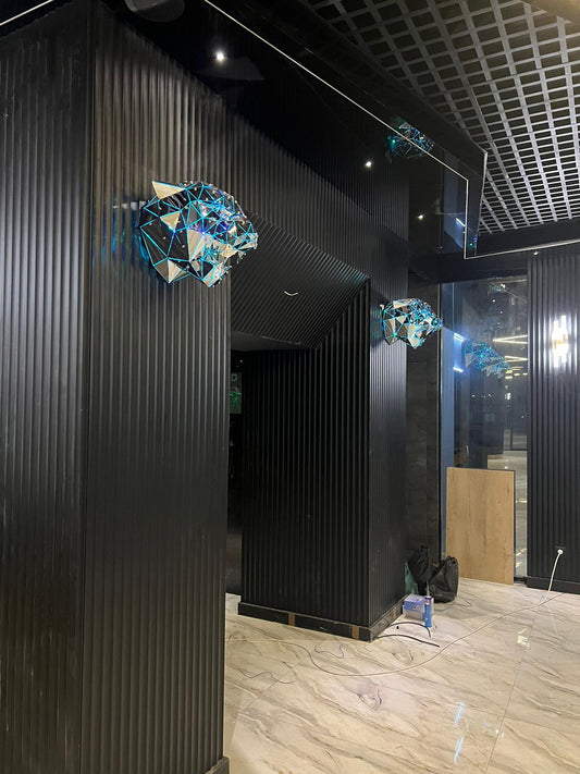 Geometric metallic animal head sculptures mounted on a black ribbed wall in a modern interior