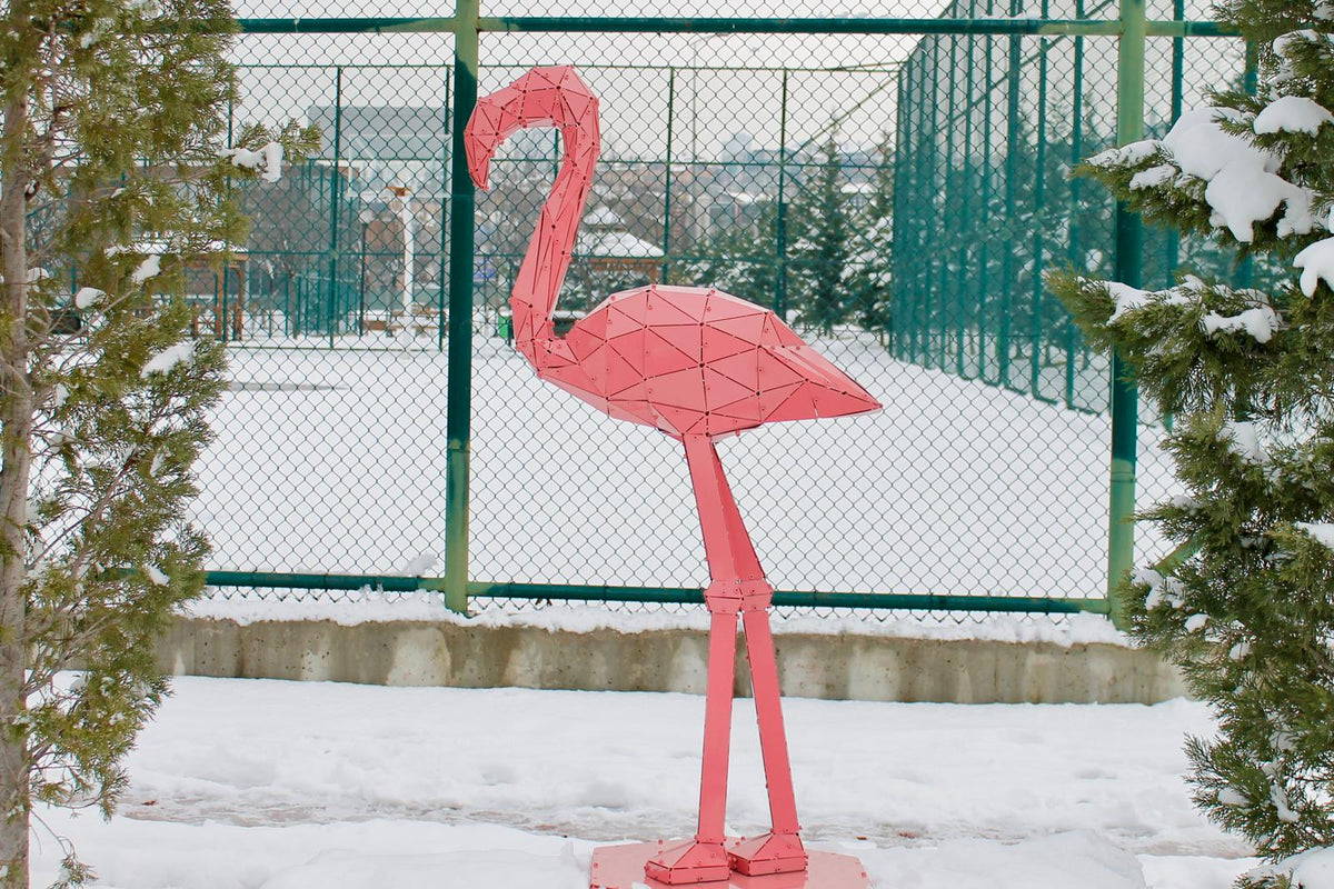Geometric pink metal flamingo sculpture in a snowy outdoor setting