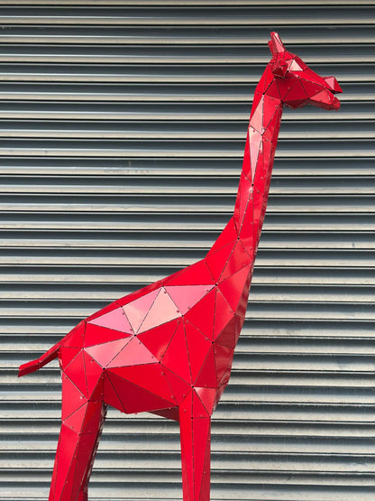 Geometric red metal giraffe sculpture against a grey corrugated background