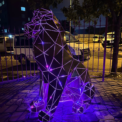 Geometric metal lion sculpture with purple LED lighting at night