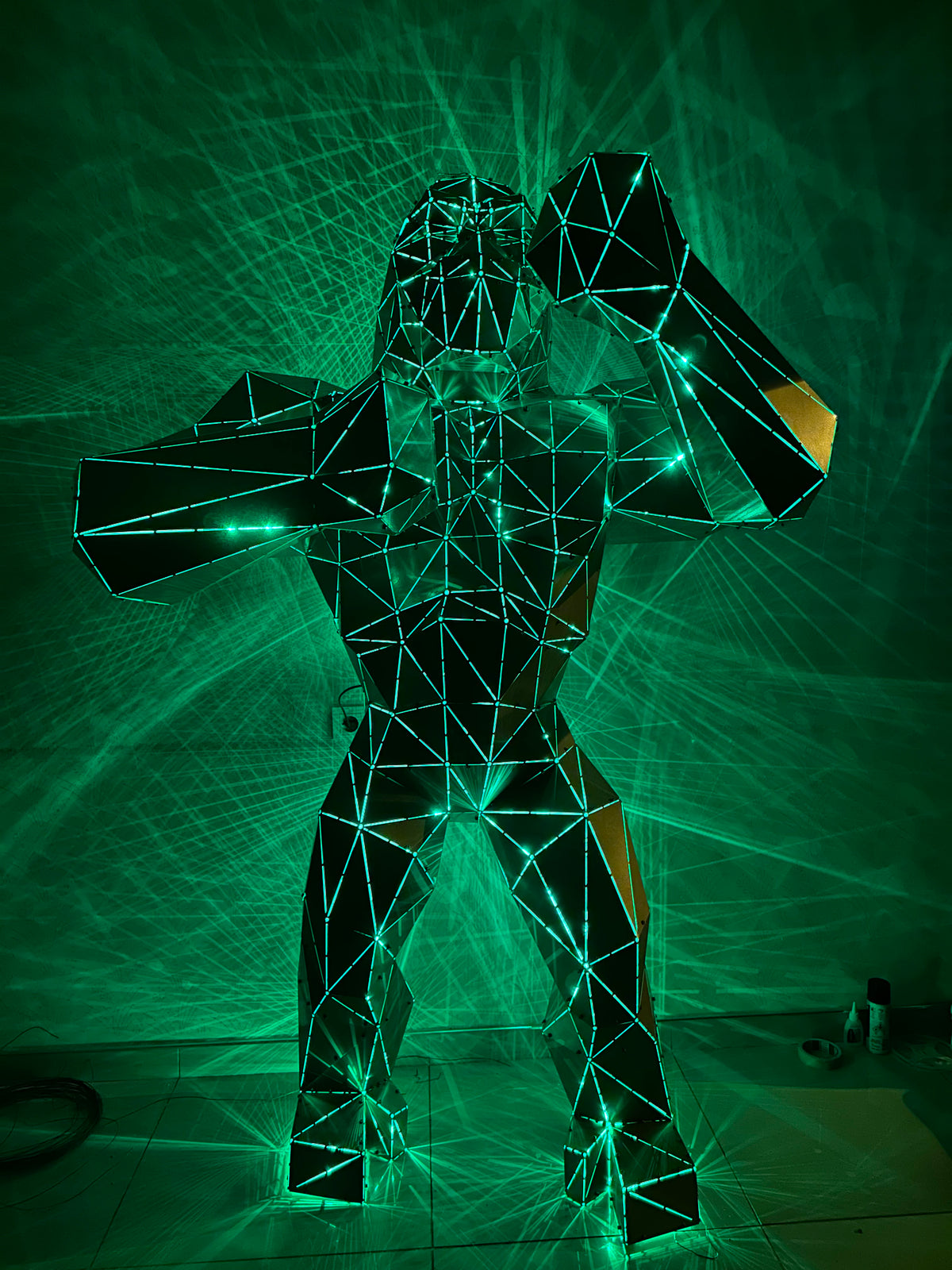 Geometric wireframe gorilla sculpture illuminated by green laser lights