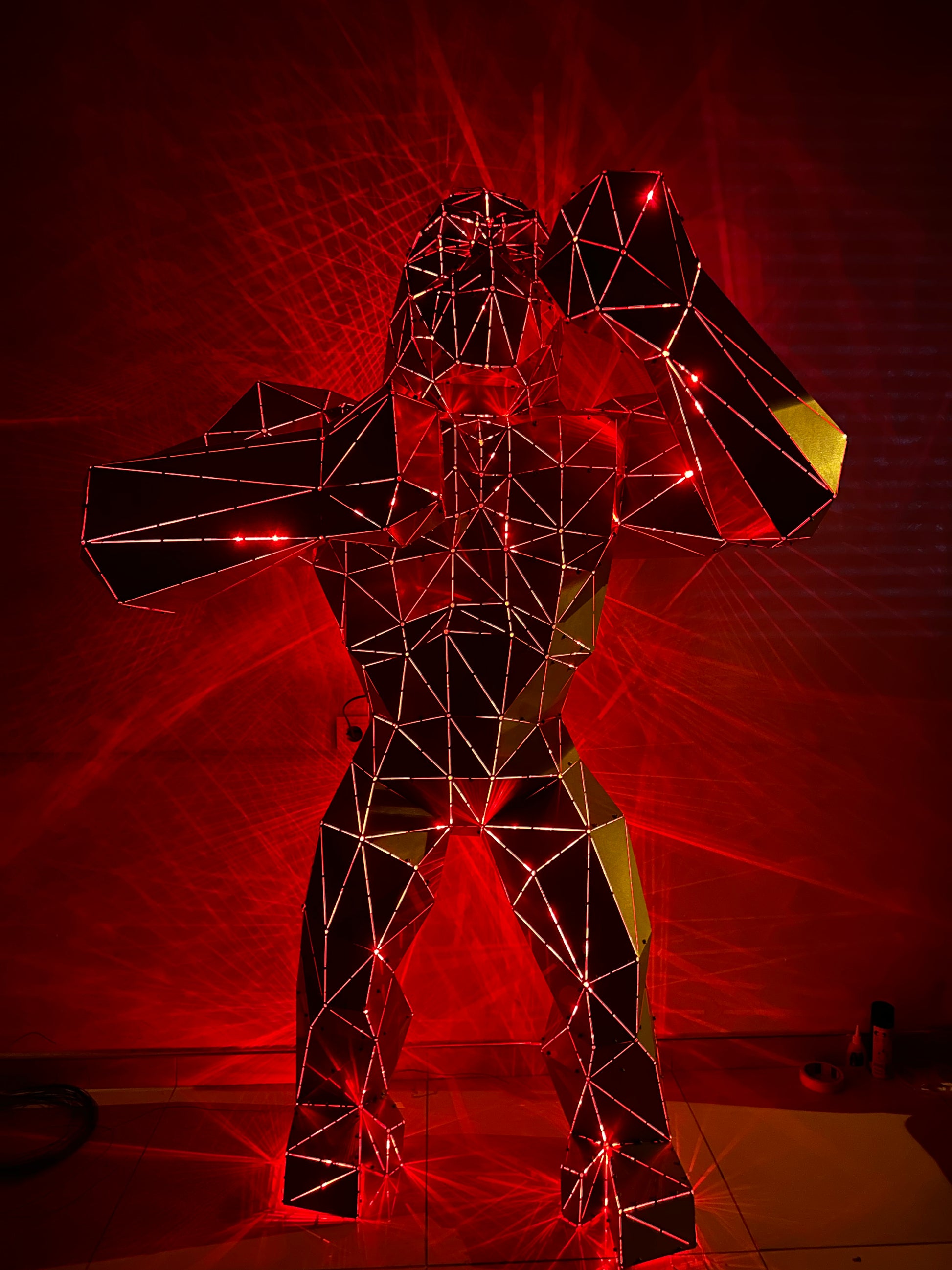 Geometric wireframe gorilla sculpture illuminated by red laser lights
