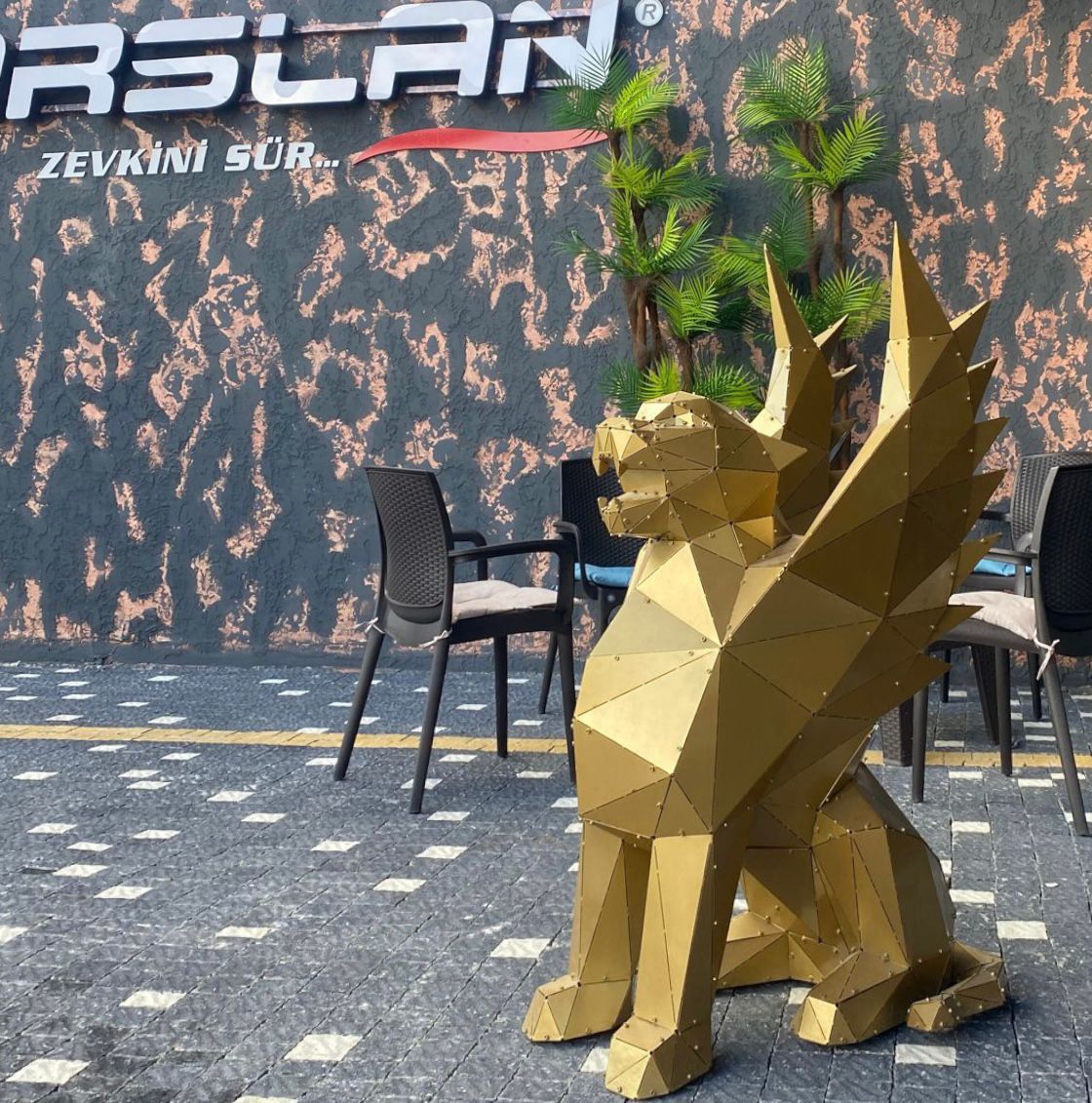 Gold geometric griffin metal sculpture in a modern outdoor setting