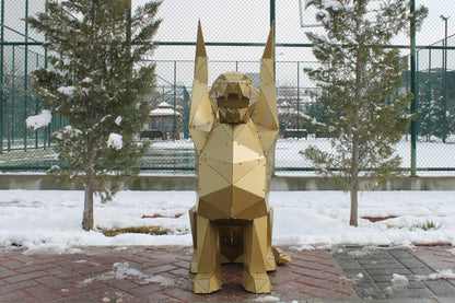 Gold geometric metal griffin sculpture seated with raised wings in a snowy outdoor setting