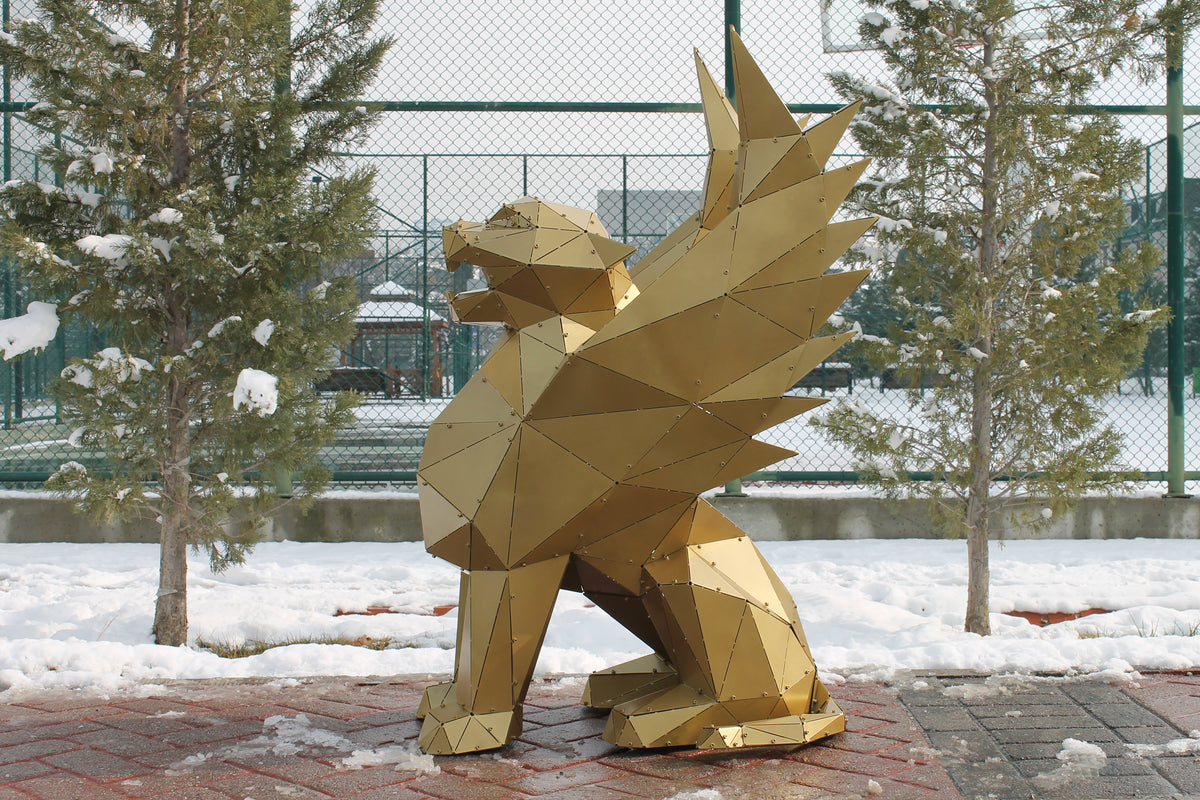 Gold geometric metal griffin sculpture in a snowy outdoor setting