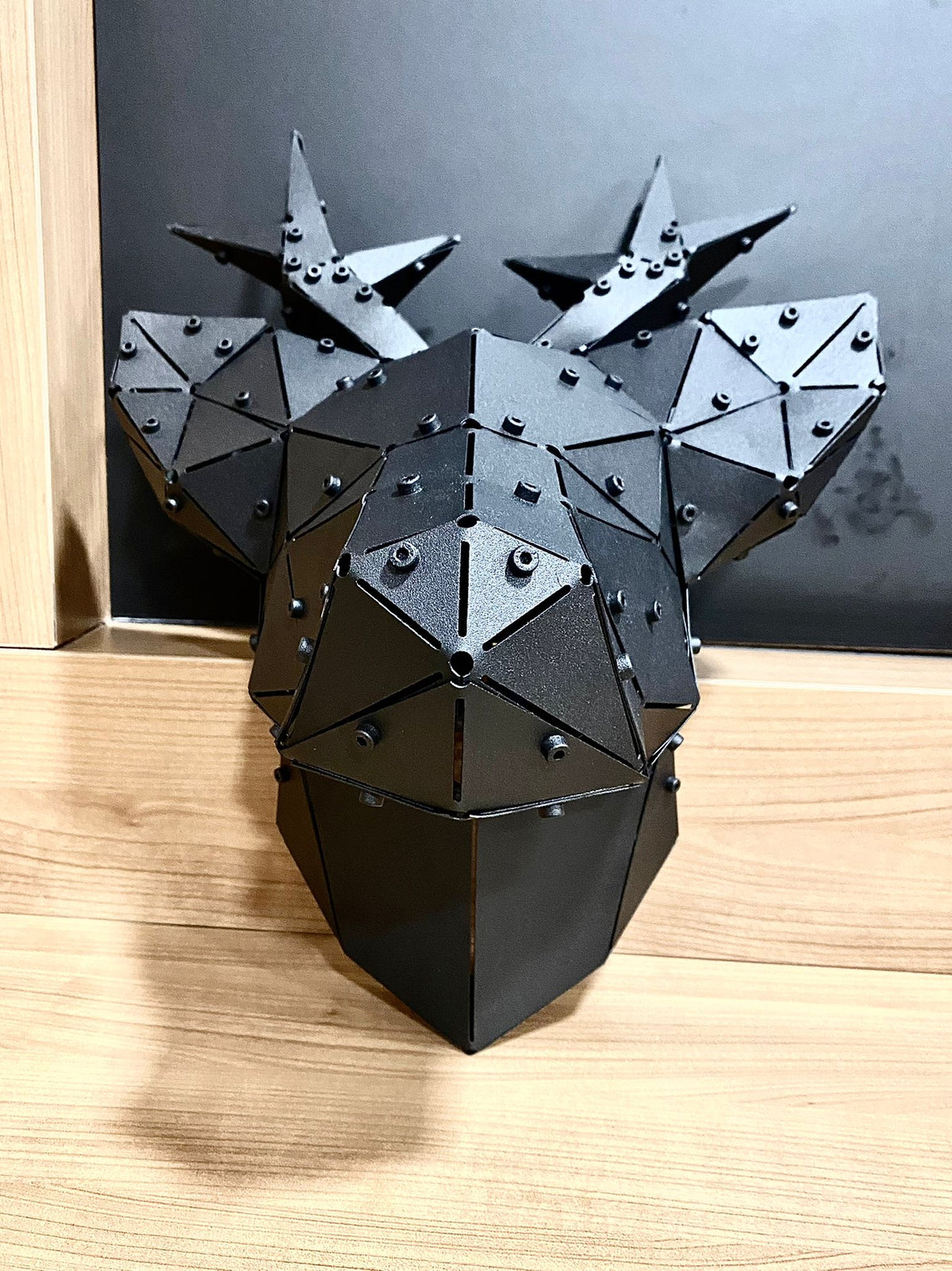 Handcrafted black metal geometric deer head sculpture with antlers on a wooden surface