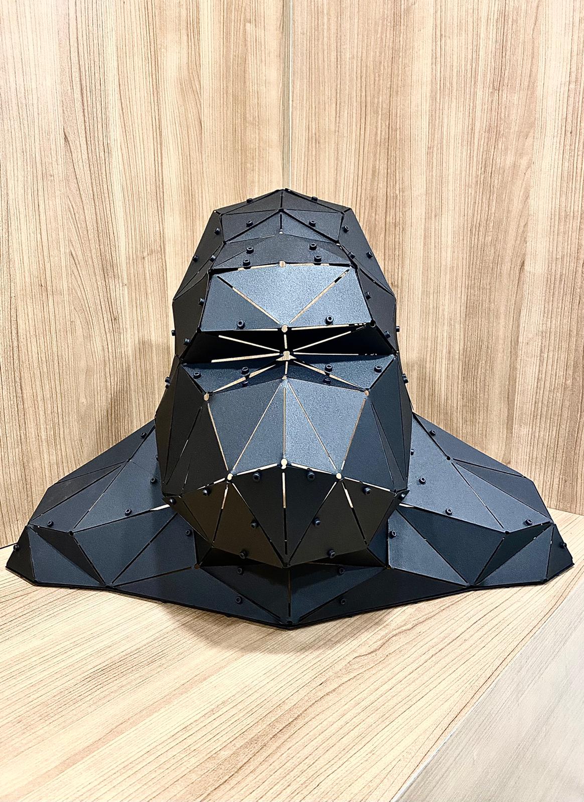 Handcrafted black metal geometric gorilla head sculpture on a wooden background