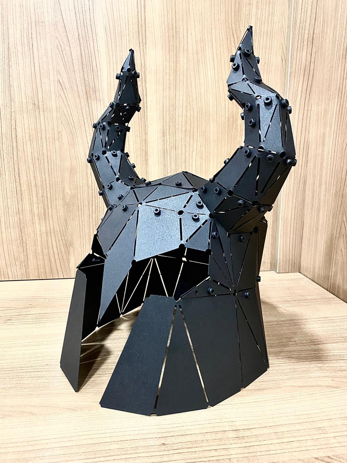 Handcrafted black metal low-poly horned helmet sculpture with raised horns on a wooden surface