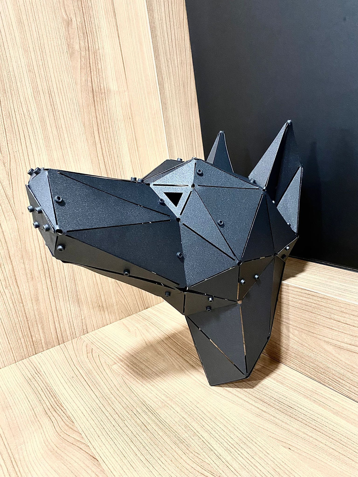 Handcrafted geometric black metal Doberman head sculpture on a light wood surface