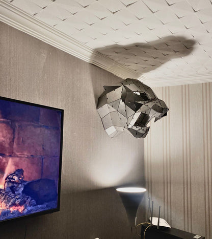 Handcrafted geometric metal panther sculpture mounted on a textured wall.
