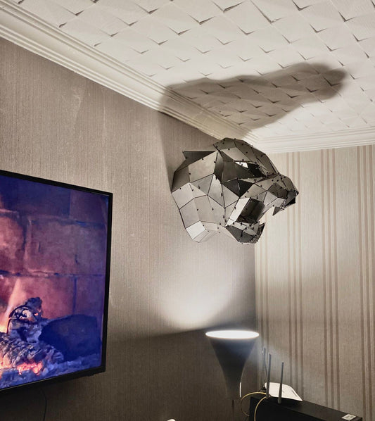Handcrafted geometric metal panther sculpture mounted on a textured wall.
