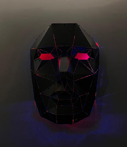 Handcrafted low-poly black metal face sculpture with glowing red eyes and pink accents.