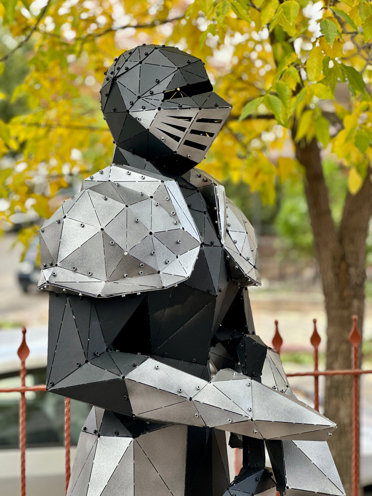 Handcrafted low-poly metal knight sculpture in a garden setting