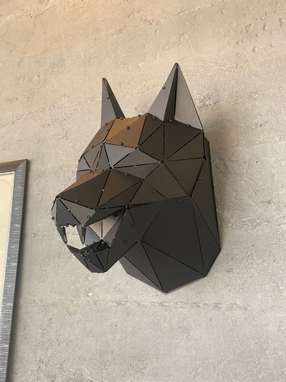 Handcrafted low-poly metal wolf head sculpture mounted on a grey concrete wall