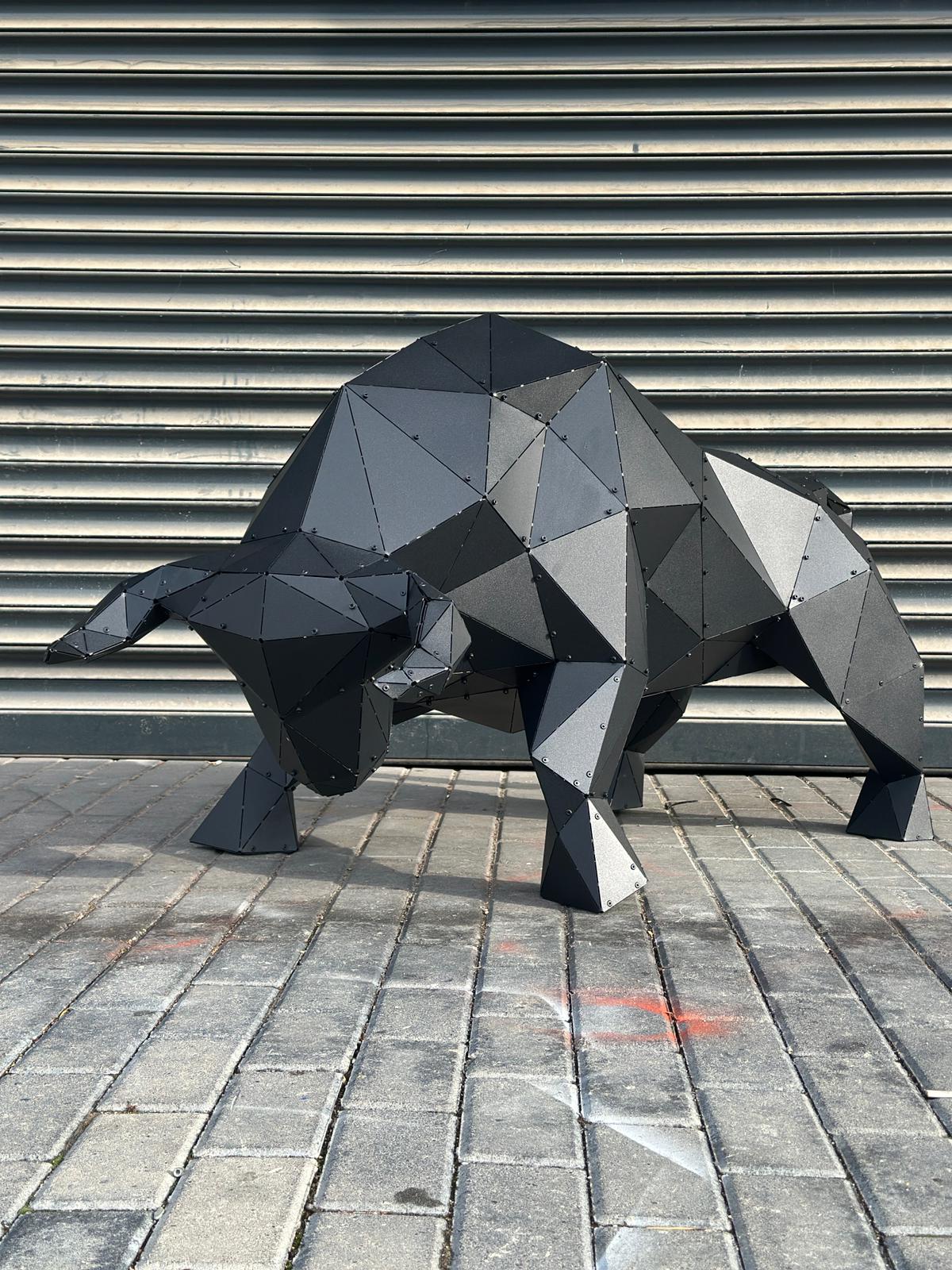 Low-poly black metal bull sculpture on a cobblestone street against a grey shutter.