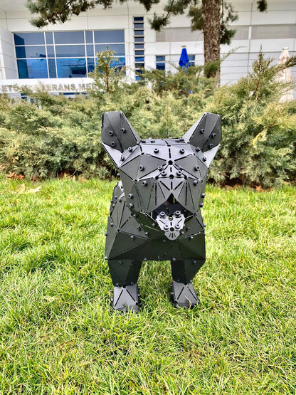 Low-poly black metal French Bulldog sculpture standing on a green grass lawn.