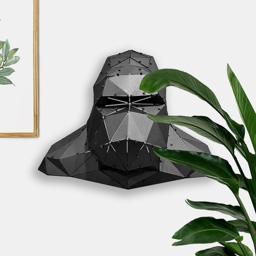 Low-poly black metal gorilla head sculpture mounted on a white wall.