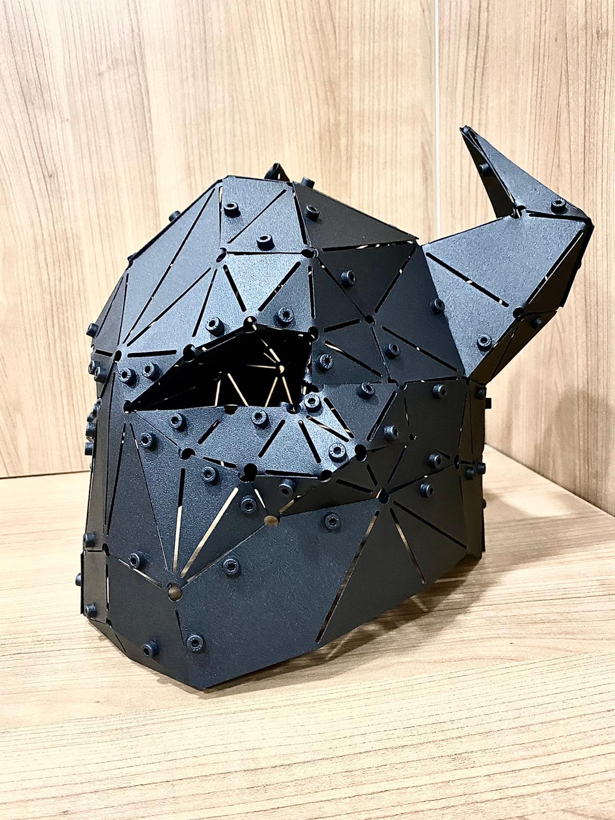 Low-poly black metal horned helmet sculpture on a wooden surface, side view