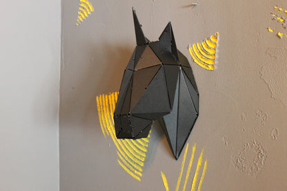 Low-poly black metal horse head sculpture mounted on a grey wall with yellow accents.