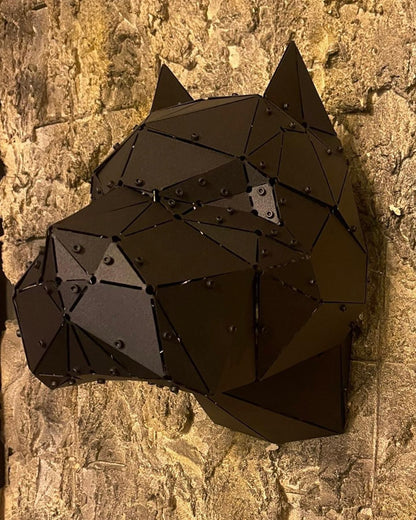 Low-poly black metal pitbull head sculpture mounted on a textured stone wall