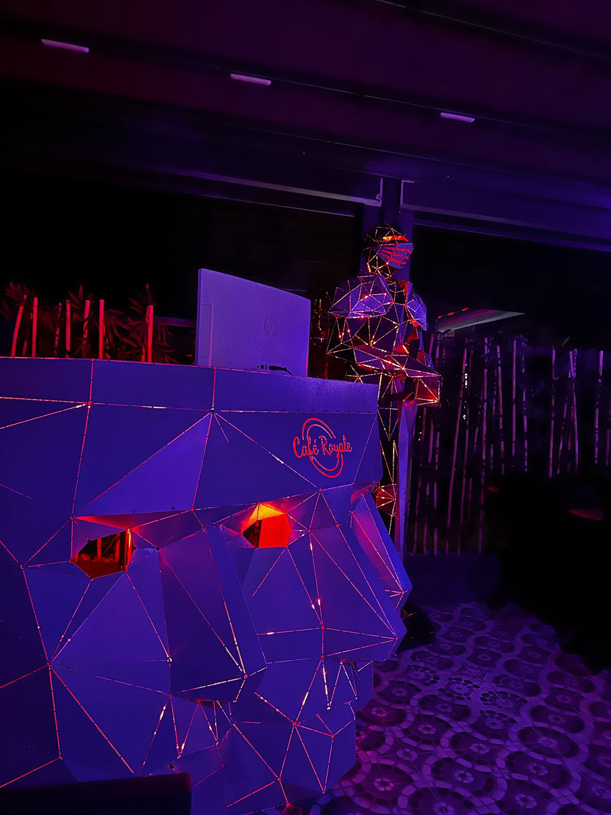 Low-poly geometric metal gorilla sculpture with red neon accents in a dim setting.