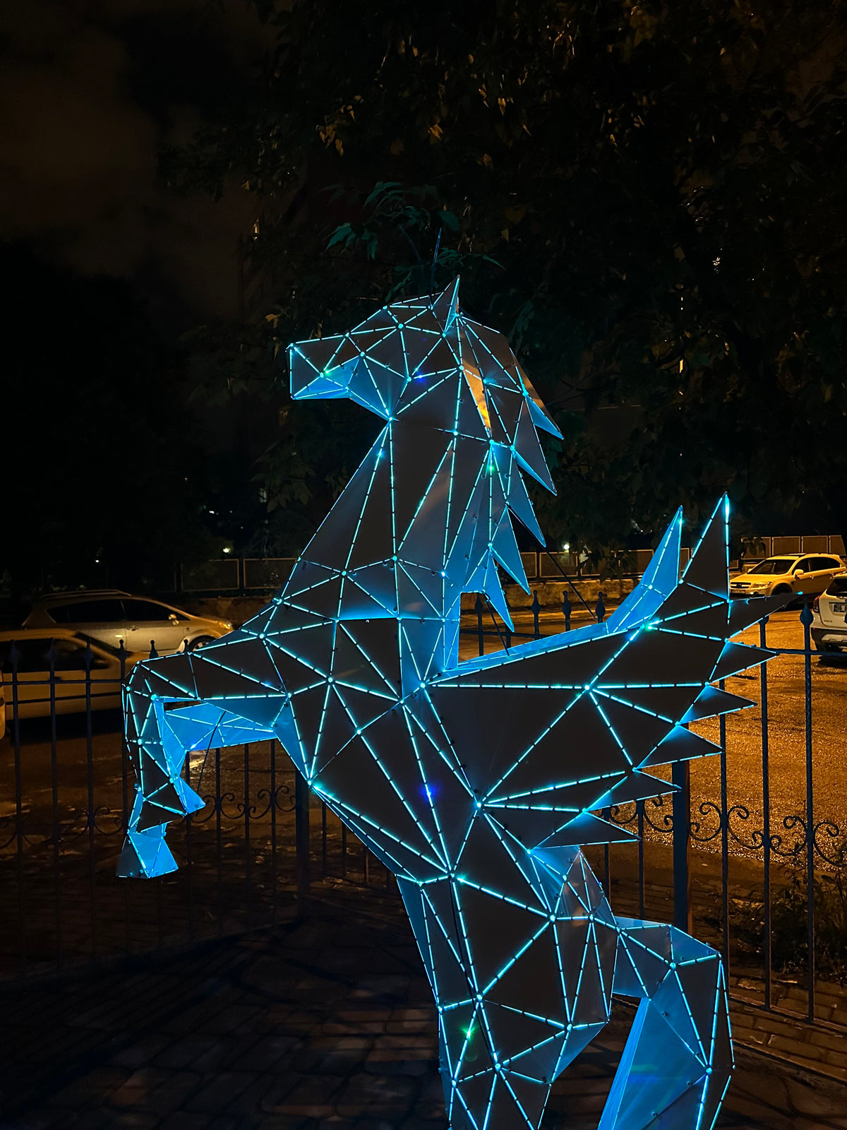 Low-poly geometric Pegasus winged horse sculpture with glowing blue neon lights at night