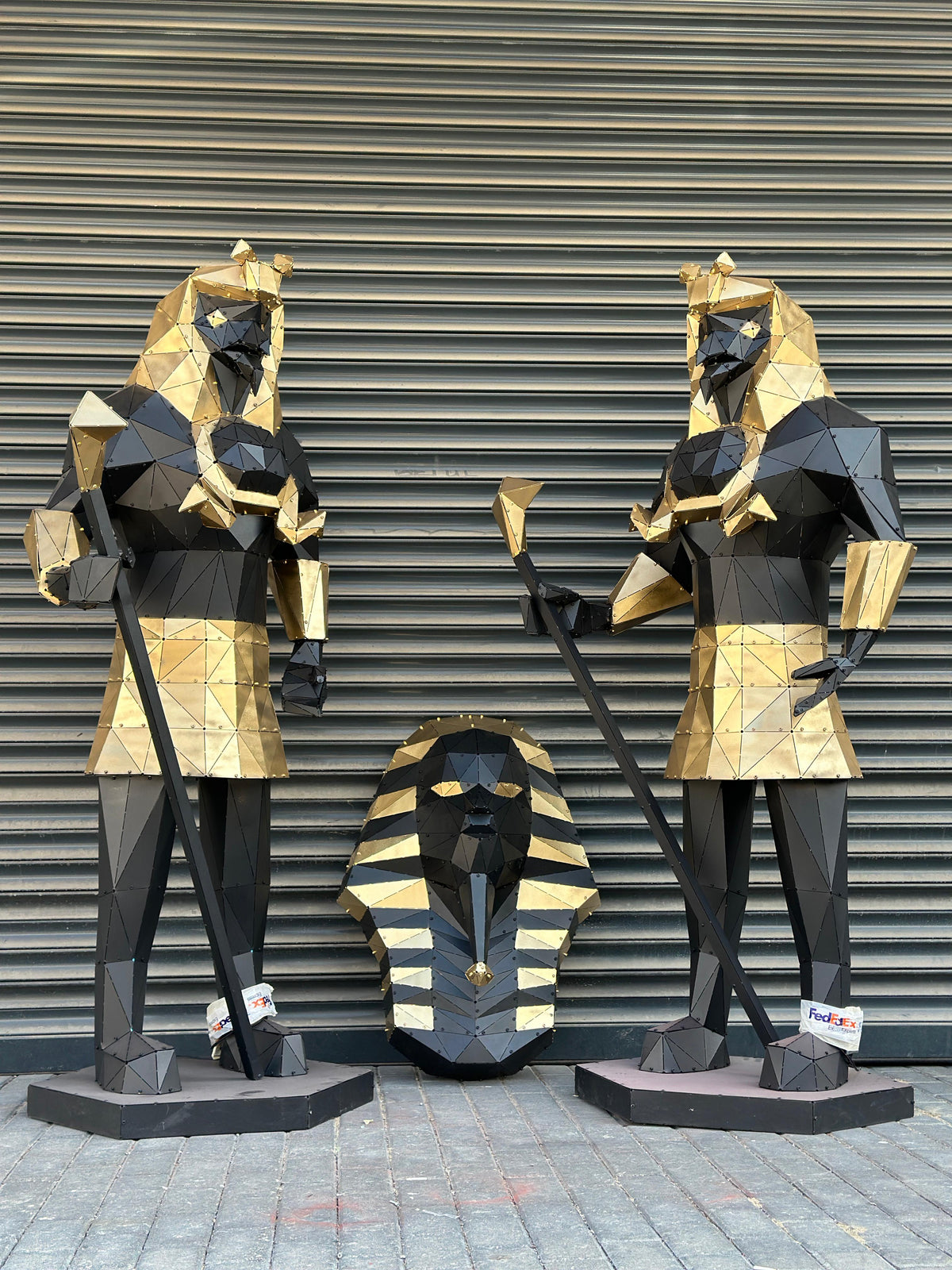 Low-poly gold and black metal Egyptian sculptures of pharaohs and a sphinx head.
