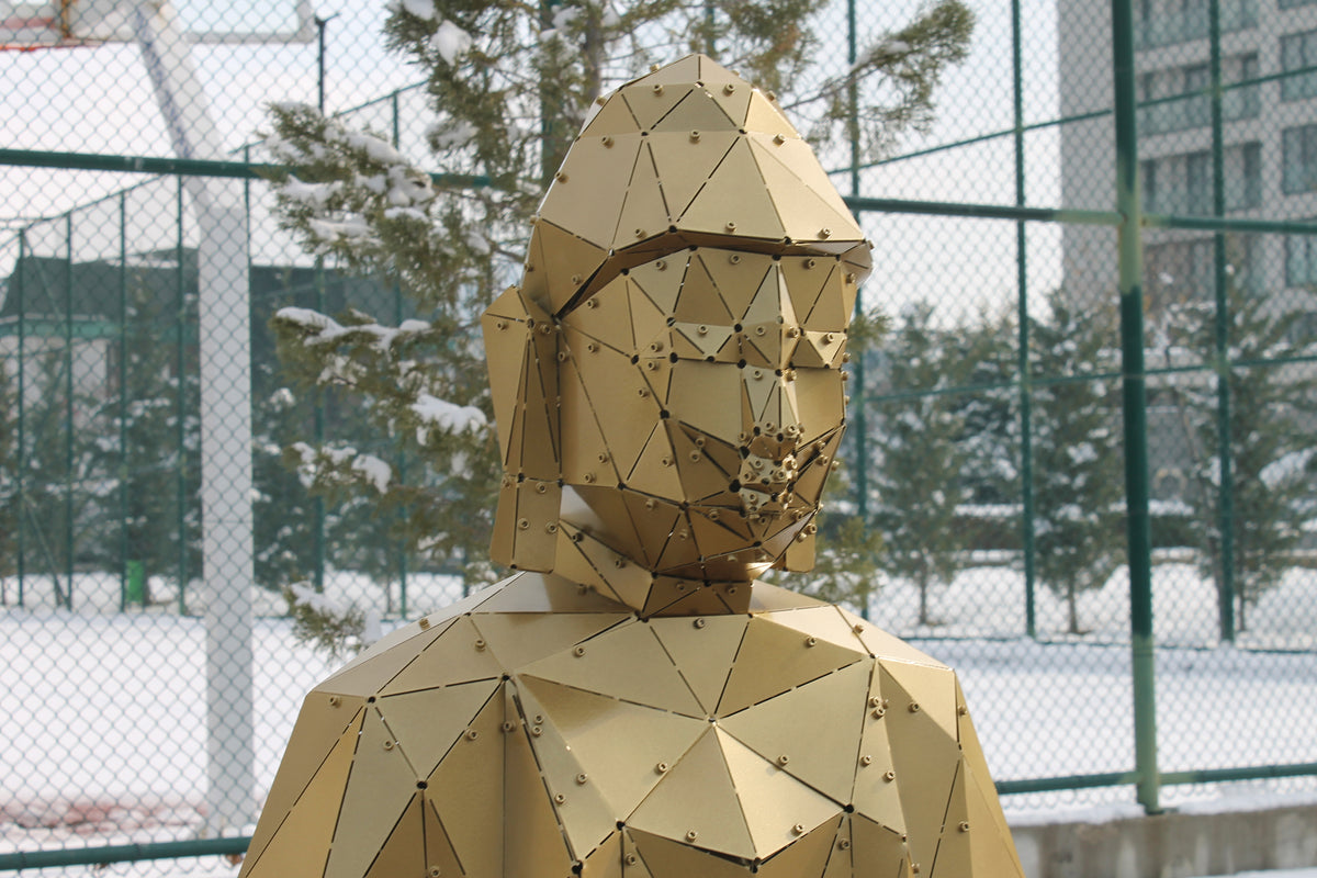 Close-up of low-poly gold metal Buddha face with elongated ears outdoors