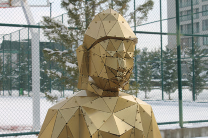 Close-up of low-poly gold metal Buddha face with elongated ears outdoors