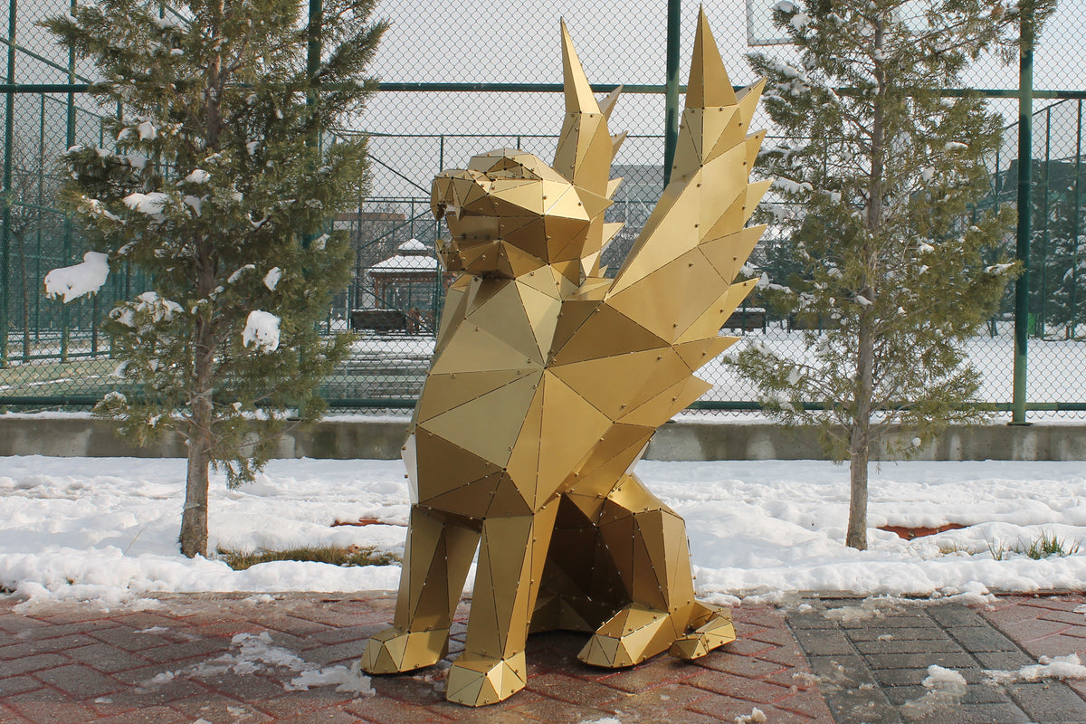 Low-poly golden metal griffin sculpture in a snowy outdoor setting