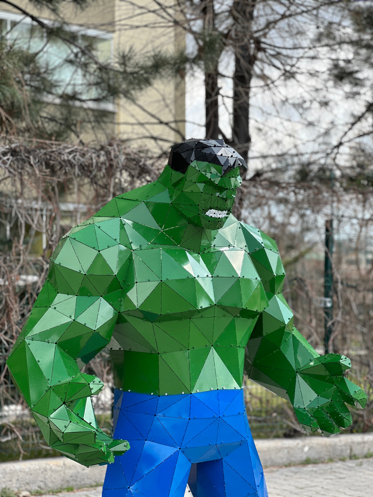 Low-poly green Hulk metal sculpture with blue pants in a geometric handcrafted style