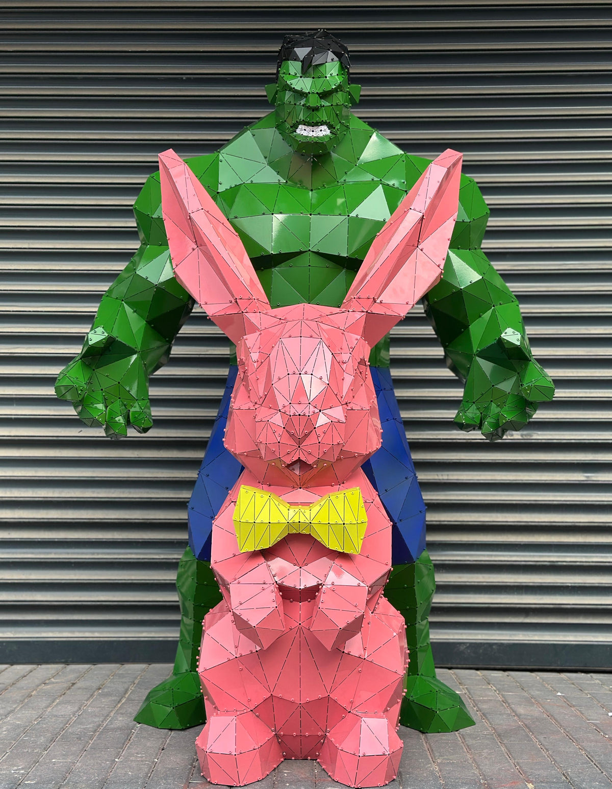 Low-poly metal sculptures of a green Hulk and a pink rabbit with a yellow bowtie.