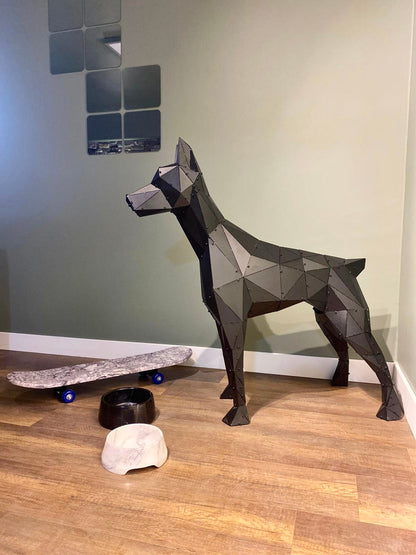 Low-poly handcrafted metal dog sculpture with a skateboard and bowls on a wooden floor.