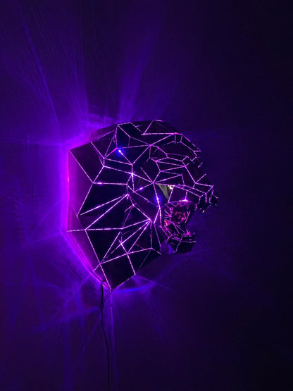 Low-poly luxury metal lion head sculpture in profile illuminated by purple neon lights