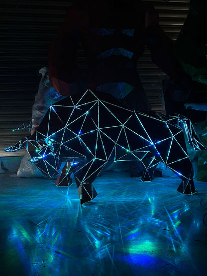 Low-poly metal bull sculpture with blue LED lighting on a reflective surface