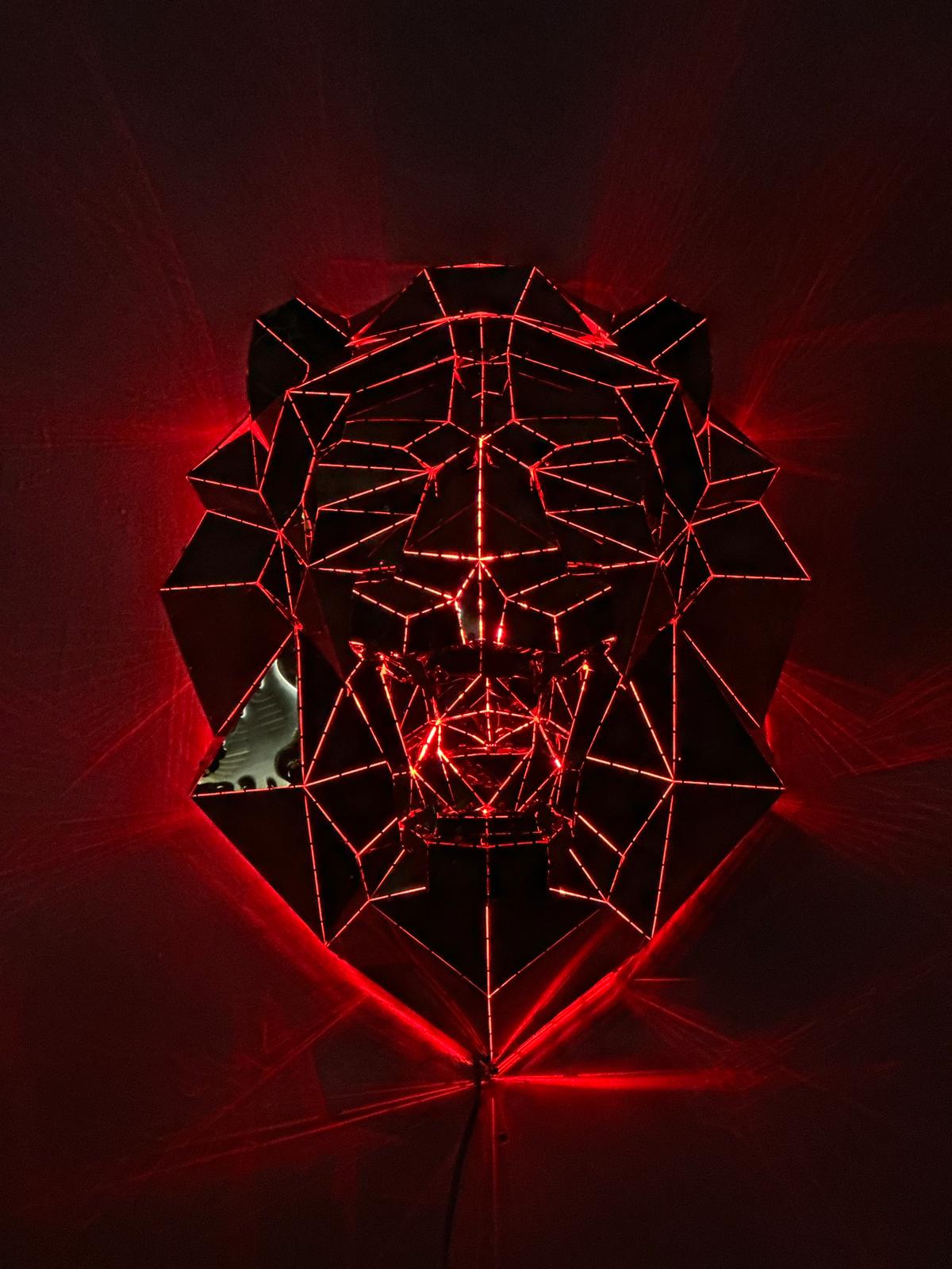 Low poly metal lion head sculpture illuminated with red neon light