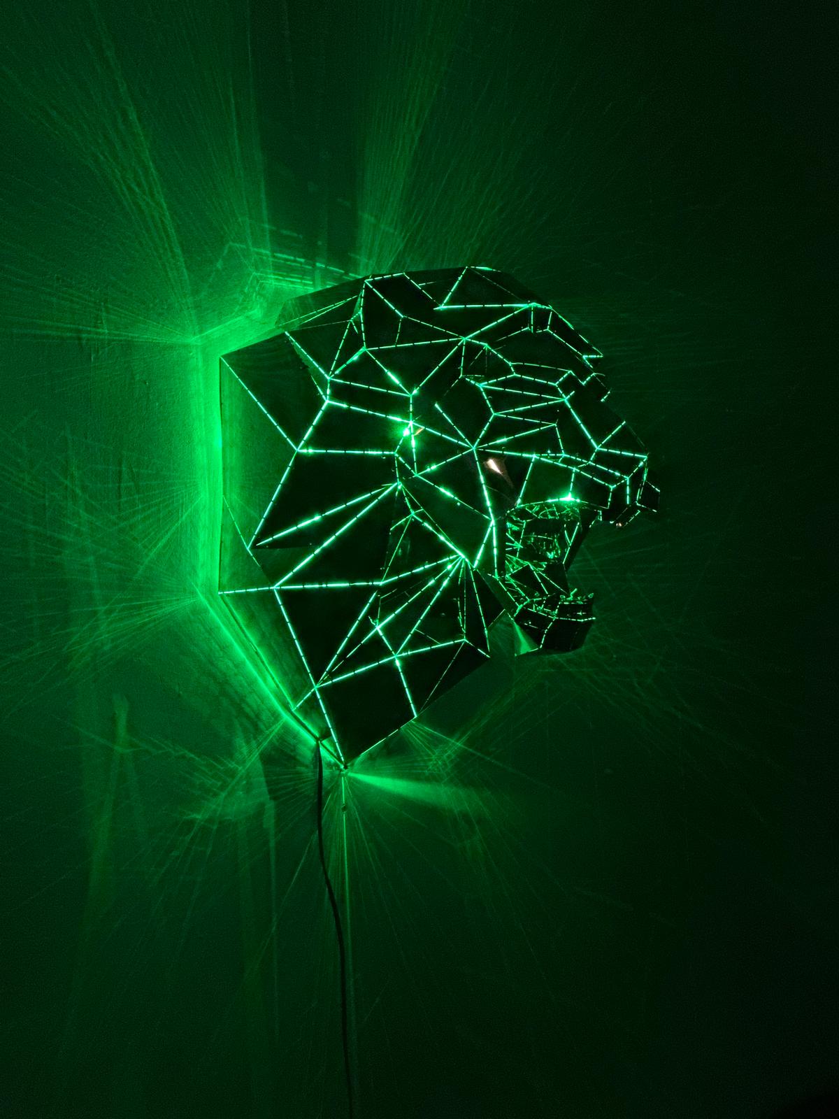 Low-poly metal lion head sculpture illuminated by vibrant green laser lights