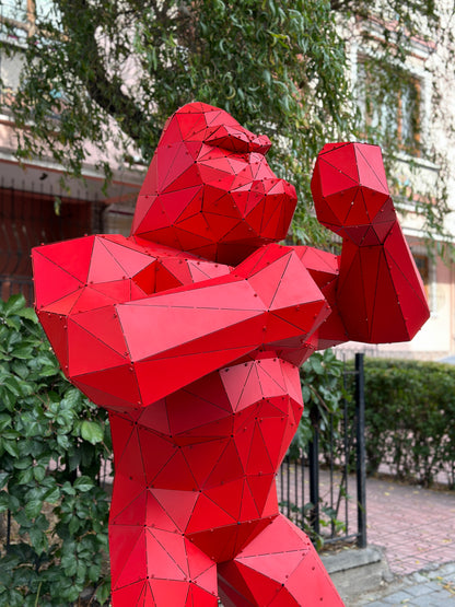 Low-poly red metal gorilla sculpture in a garden setting