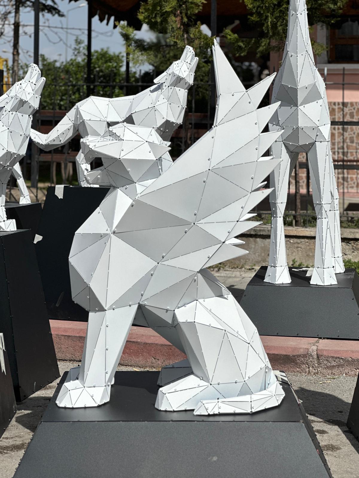 Low-poly white metal sculpture of a winged mythological creature on a black pedestal.