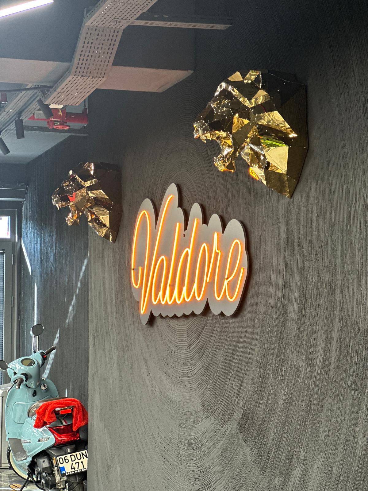 Luxury gold faceted lion head wall sculptures with an orange neon sign on a textured dark wall